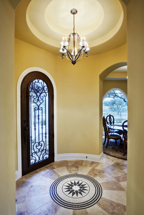 Example of a large tuscan travertine floor and beige floor entryway design in Austin with yellow walls and a brown front door