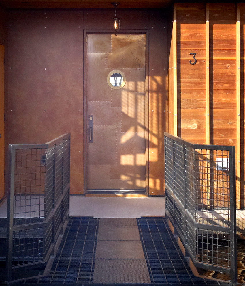 シアトルにあるラグジュアリーな小さなインダストリアルスタイルのおしゃれな玄関ドア (茶色い壁、コンクリートの床、金属製ドア、ベージュの床) の写真