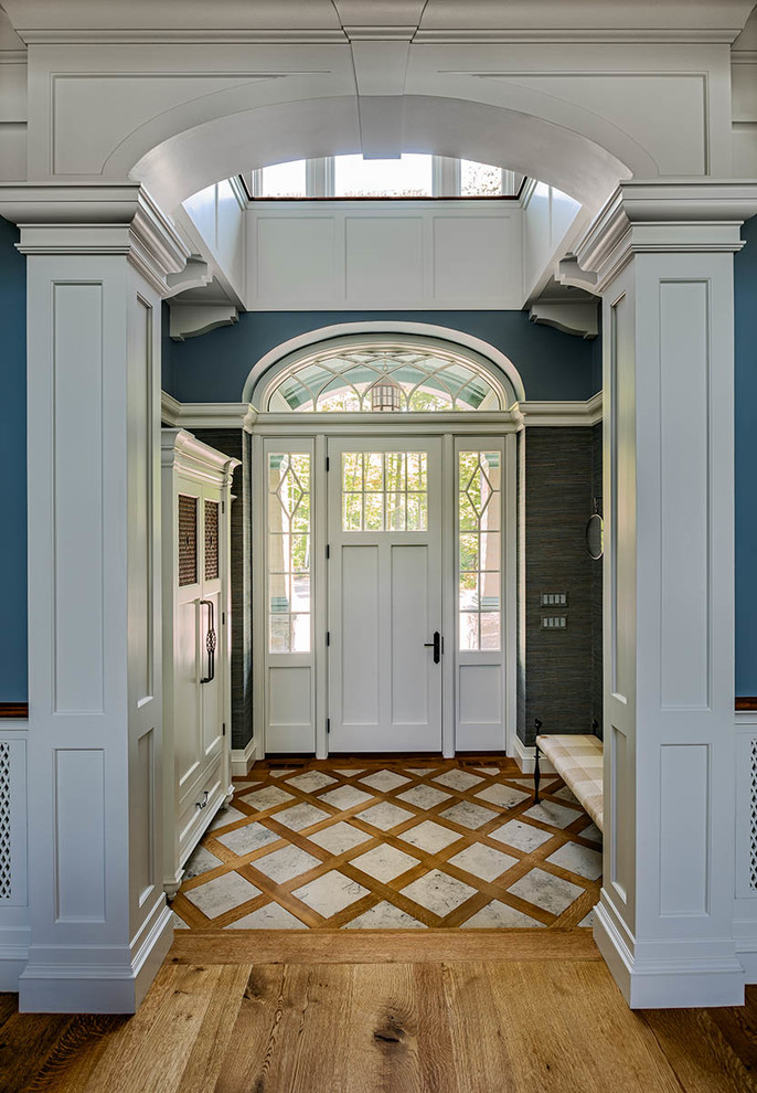 Klassisches Foyer mit blauer Wandfarbe, braunem Holzboden, Einzeltür, weißer Haustür und braunem Boden in Boston