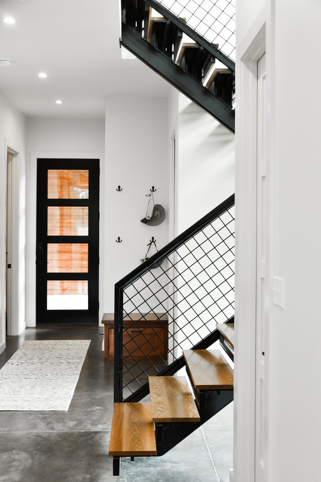 Inspiration pour une entrée minimaliste de taille moyenne avec un couloir, un mur blanc, sol en béton ciré, une porte simple, une porte noire et un sol gris.