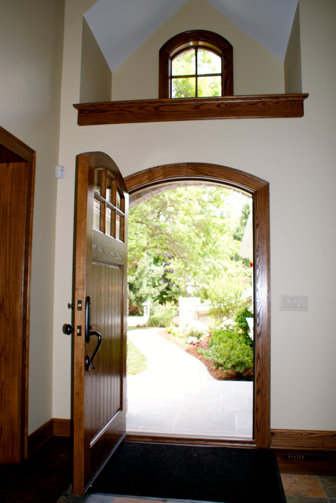 Cette photo montre une porte d'entrée chic avec un mur beige, un sol en bois brun, une porte simple et une porte en bois brun.