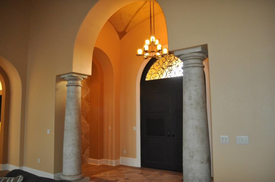 Ejemplo de entrada mediterránea con suelo de travertino, puerta doble y puerta metalizada