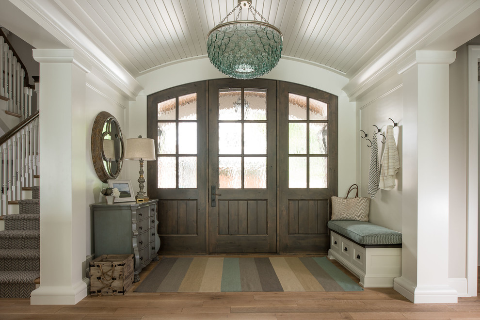 Ejemplo de puerta principal marinera con paredes blancas, suelo de madera en tonos medios, puerta simple, puerta de madera oscura y suelo marrón