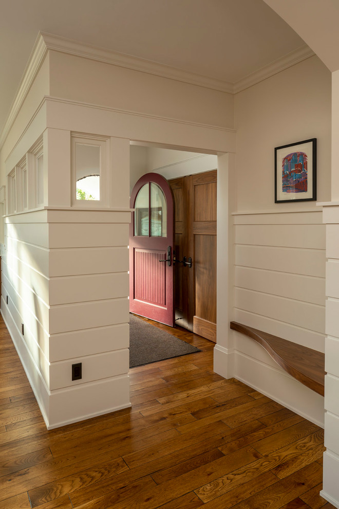 Foto på en liten vintage foajé, med vita väggar, mörkt trägolv, en enkeldörr, en röd dörr och brunt golv