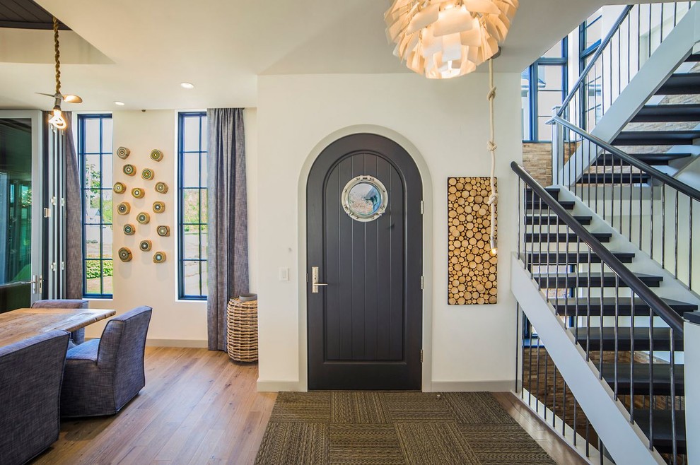 This is an example of a large nautical foyer in Chicago with white walls, light hardwood flooring, a single front door and a grey front door.