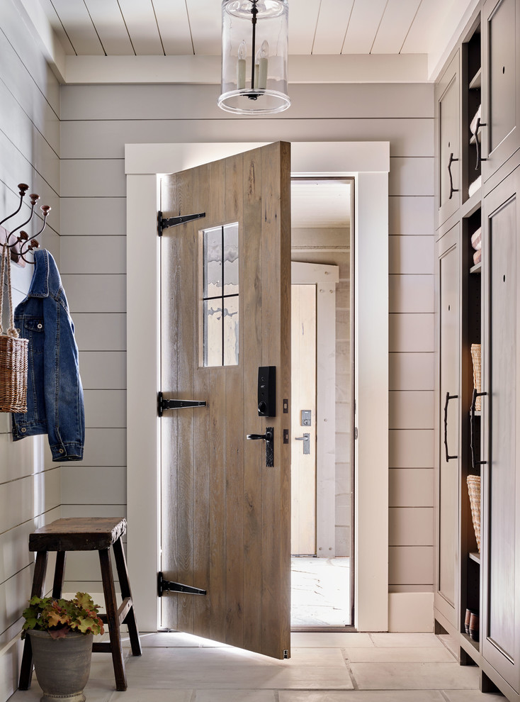 This is an example of a rustic boot room with grey walls, a single front door, a medium wood front door and grey floors.