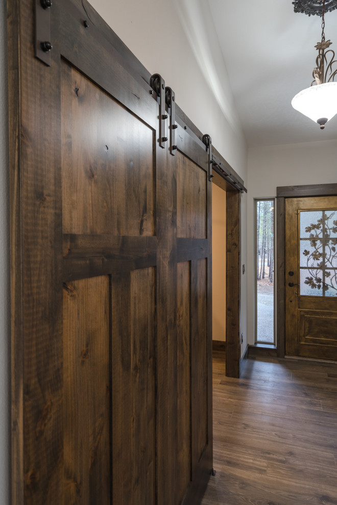 Imagen de distribuidor rústico extra grande con paredes grises, suelo laminado, puerta simple, puerta de madera oscura y suelo marrón