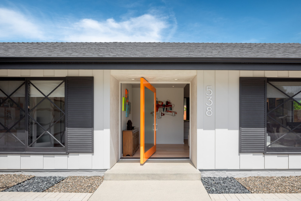 Imagen de puerta principal actual con paredes blancas, suelo de madera clara, puerta pivotante, puerta naranja y suelo beige