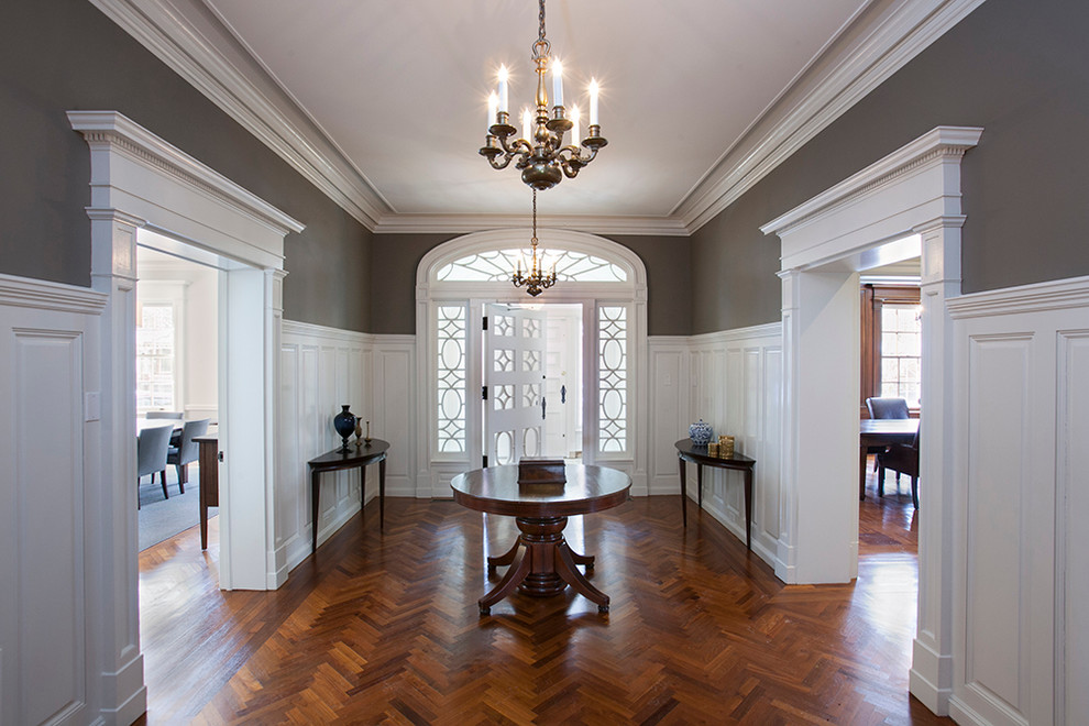 Inspiration pour un hall d'entrée traditionnel de taille moyenne avec un mur gris, un sol en bois brun et une porte blanche.