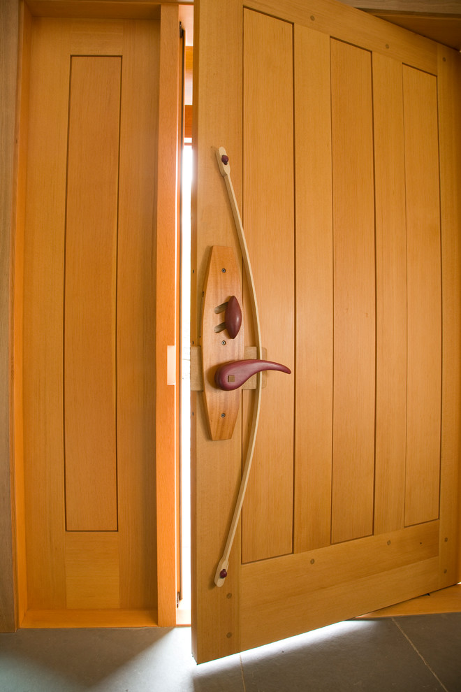 Foto di una porta d'ingresso contemporanea con pareti bianche, pavimento in ardesia, una porta a pivot e una porta in legno bruno