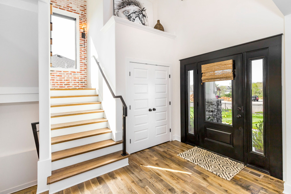 Источник вдохновения для домашнего уюта: большая входная дверь в стиле кантри с белыми стенами, паркетным полом среднего тона, одностворчатой входной дверью, черной входной дверью и коричневым полом