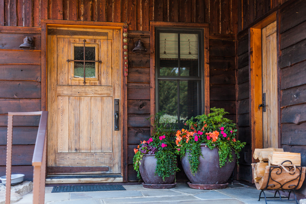 Immagine di una porta d'ingresso stile rurale con pareti marroni, una porta singola, una porta in legno bruno e pavimento grigio