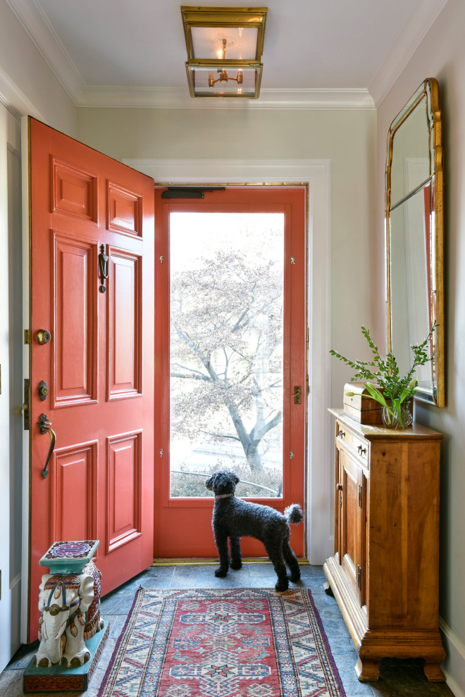 Imagen de entrada clásica con paredes beige, puerta simple, puerta roja y suelo gris