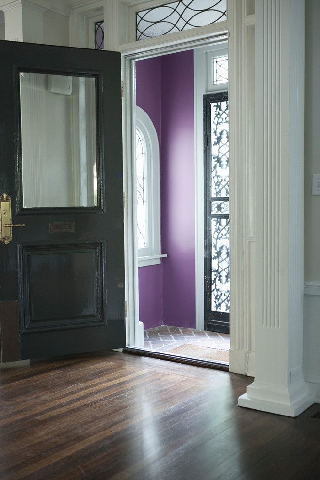 Inredning av en klassisk stor foajé, med en dubbeldörr, en svart dörr, lila väggar och mörkt trägolv