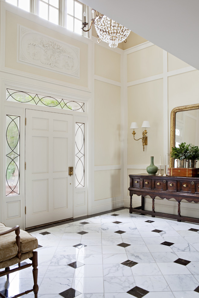 Exempel på en stor klassisk foajé, med beige väggar, en enkeldörr, en vit dörr och marmorgolv