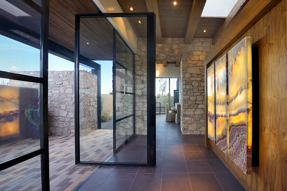 This is an example of a large hallway in Albuquerque with slate flooring, a pivot front door, a glass front door and black floors.