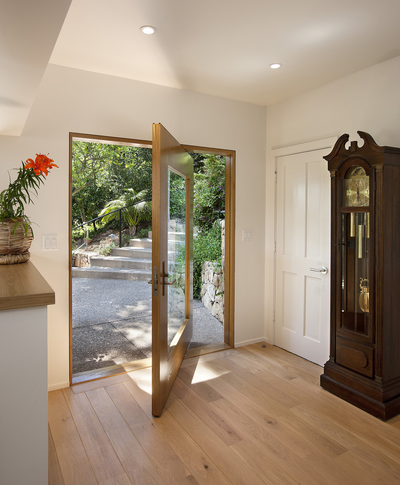 Idées déco pour une porte d'entrée contemporaine de taille moyenne avec un mur blanc, parquet clair, une porte pivot et une porte en bois brun.