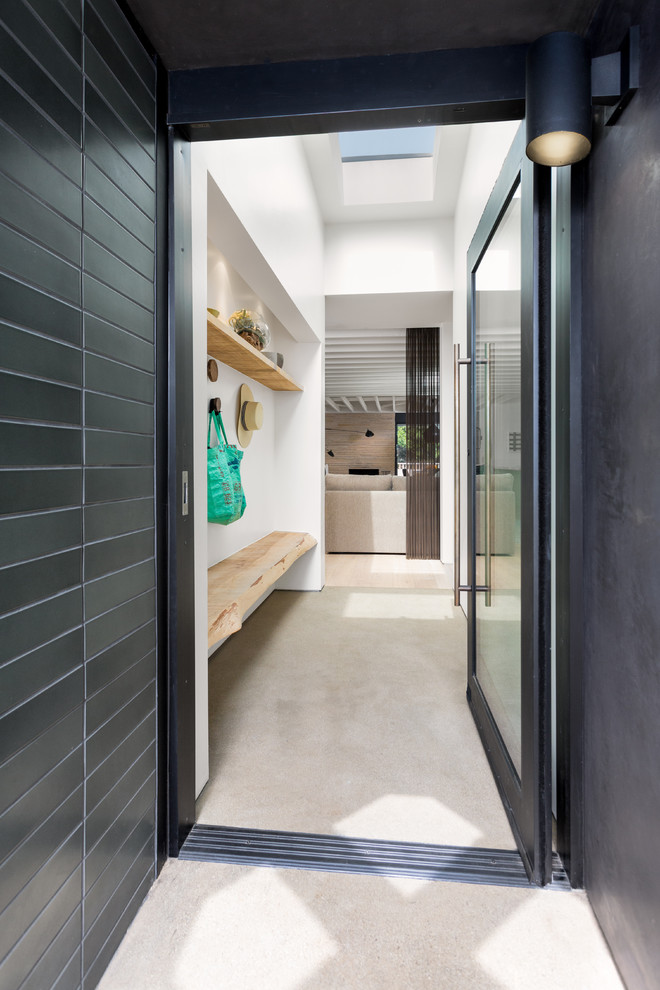 Exempel på en mellanstor modern farstu, med grå väggar, betonggolv, en pivotdörr, en svart dörr och beiget golv