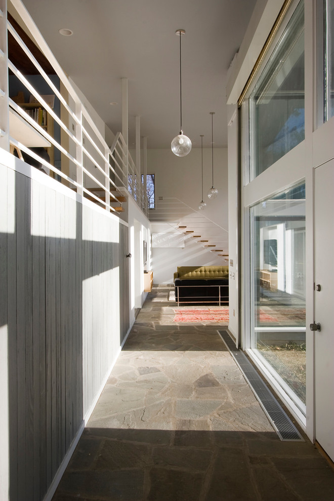 Стильный дизайн: большая узкая прихожая в стиле модернизм с серыми стенами, одностворчатой входной дверью и белой входной дверью - последний тренд