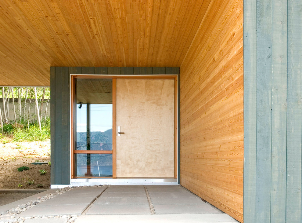 Idée de décoration pour une porte d'entrée design de taille moyenne avec sol en béton ciré, une porte simple et une porte en bois clair.