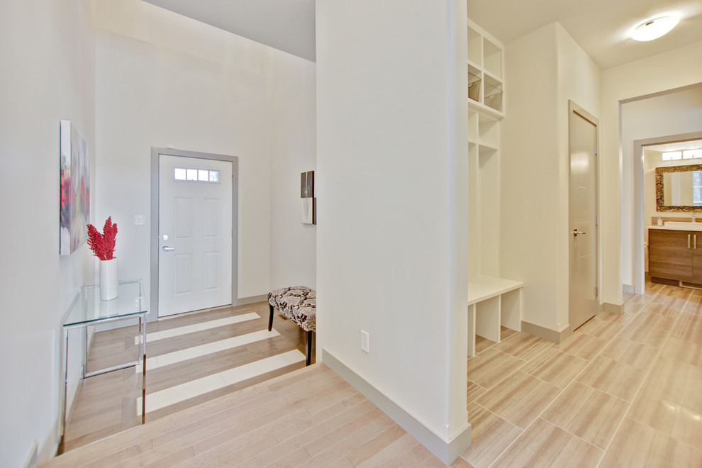 Foto di un ingresso minimalista di medie dimensioni con pareti bianche, pavimento in legno massello medio, una porta singola, una porta bianca e pavimento marrone
