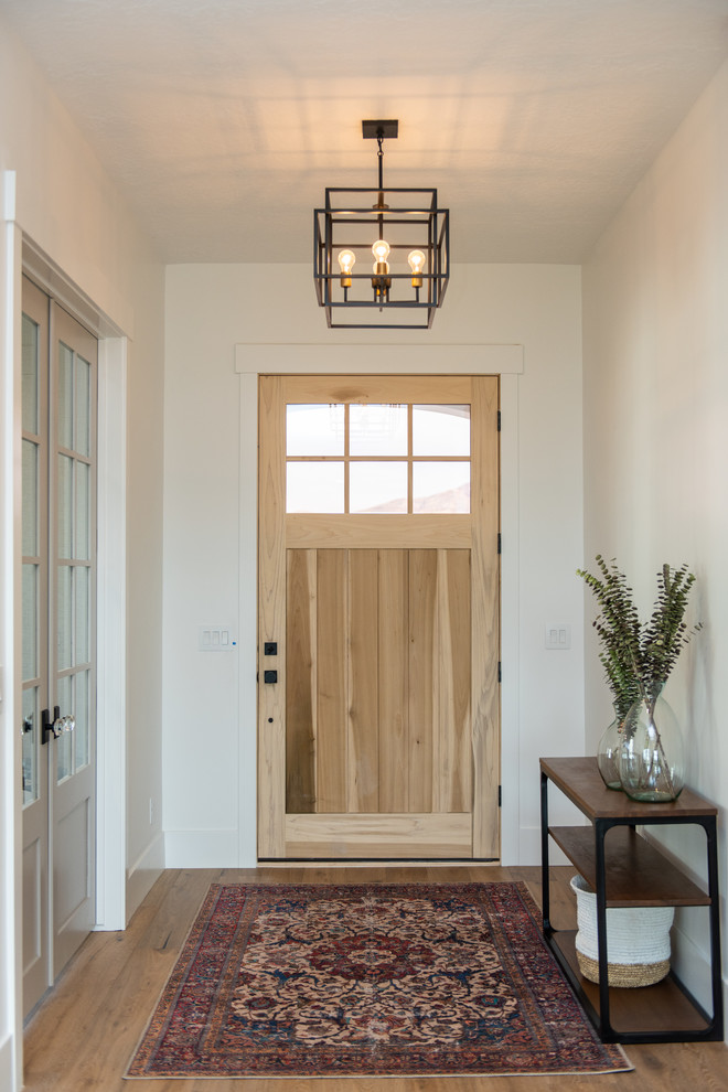 На фото: тамбур среднего размера в стиле неоклассика (современная классика) с белыми стенами, светлым паркетным полом, одностворчатой входной дверью, белой входной дверью и коричневым полом