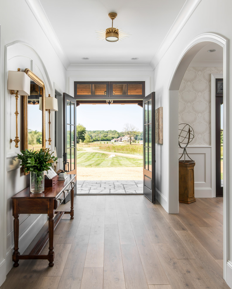 Foto de entrada grande con paredes blancas, suelo de madera en tonos medios, puerta doble, puerta negra y suelo marrón