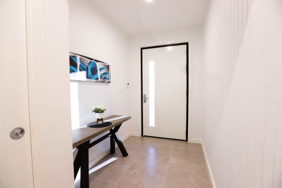 Foto de hall minimalista de tamaño medio con paredes blancas, suelo de baldosas de cerámica, puerta simple, puerta blanca, suelo beige y panelado