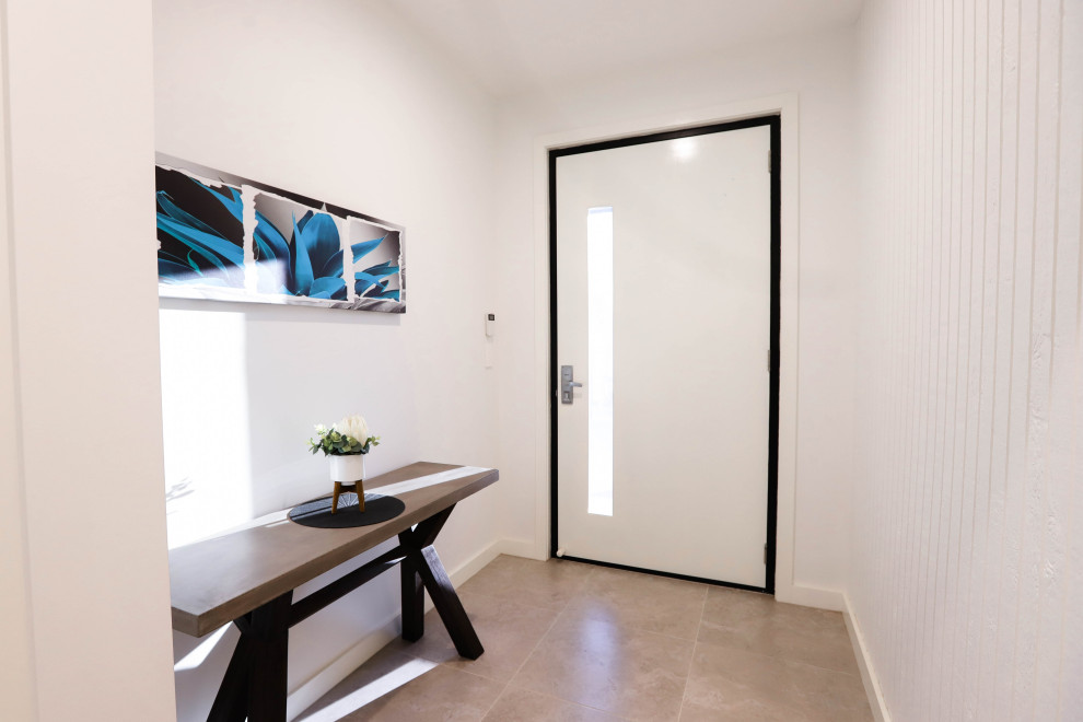 Diseño de hall minimalista de tamaño medio con paredes blancas, suelo de baldosas de cerámica, puerta simple, puerta blanca, suelo beige y panelado