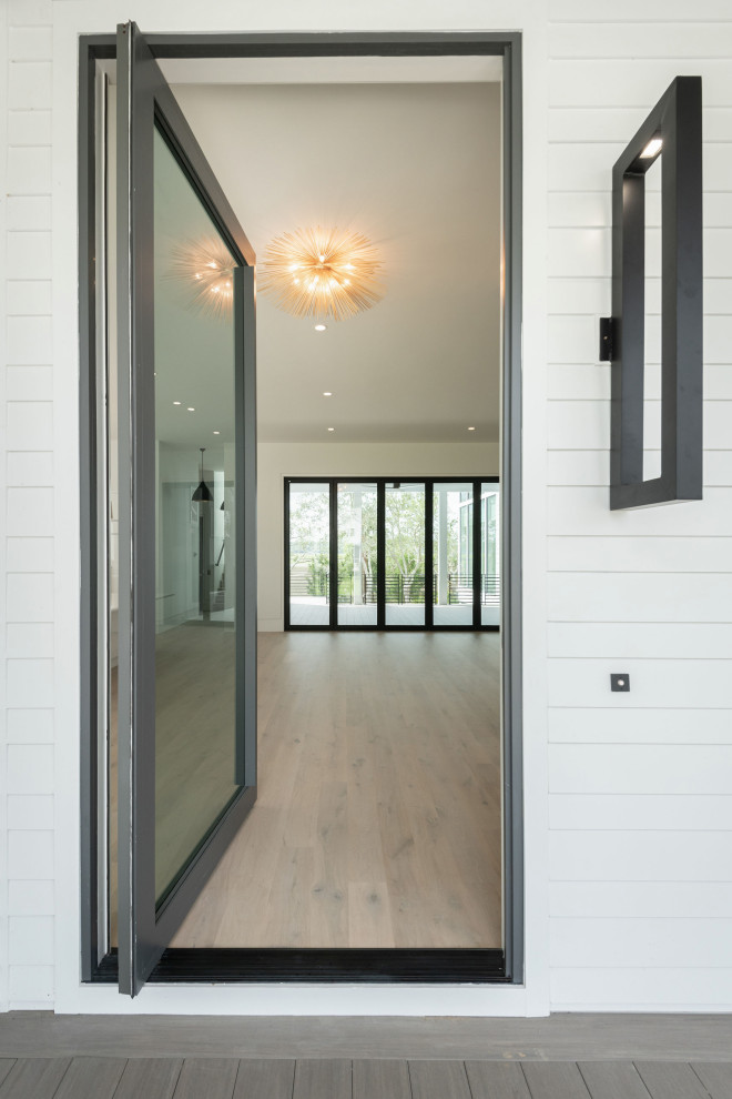 Стильный дизайн: большая входная дверь в стиле модернизм с белыми стенами, полом из ламината, поворотной входной дверью, металлической входной дверью и серым полом - последний тренд