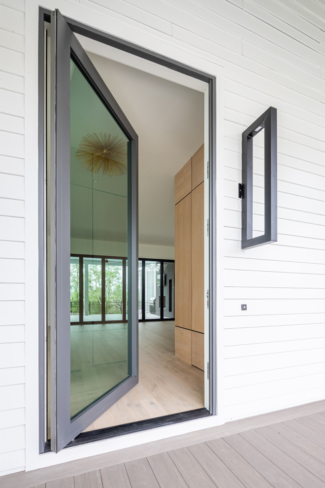 На фото: огромная входная дверь в стиле модернизм с белыми стенами, паркетным полом среднего тона, поворотной входной дверью, металлической входной дверью, серым полом, деревянным потолком и деревянными стенами с