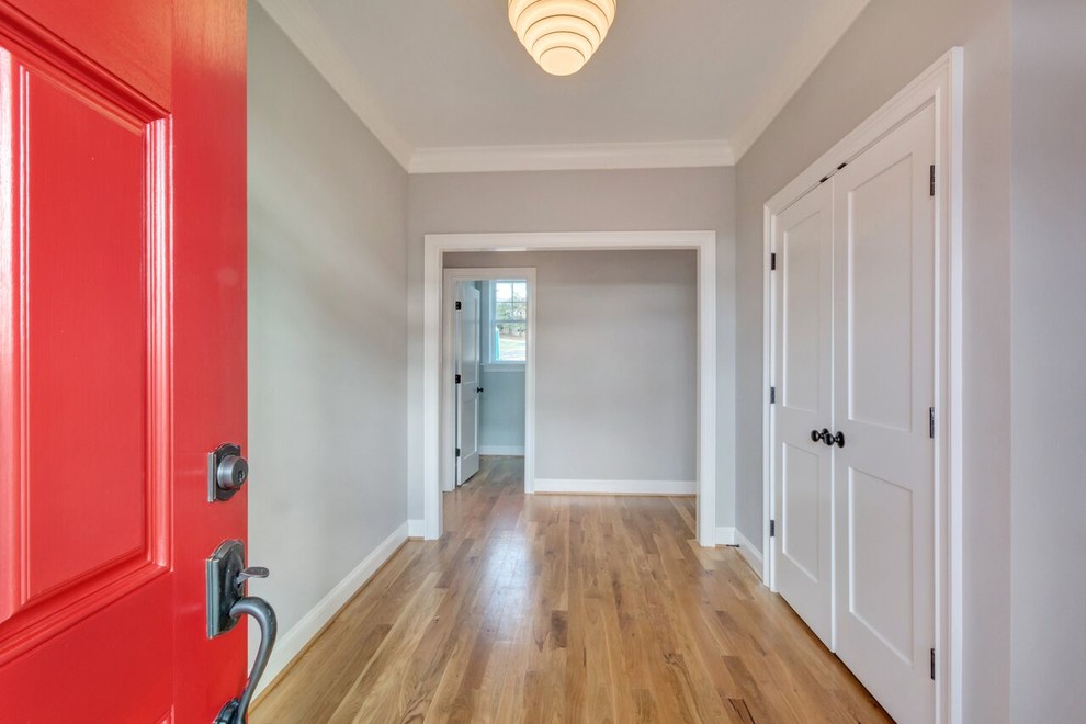 Ejemplo de hall contemporáneo con paredes grises, suelo de madera en tonos medios, puerta simple y puerta roja