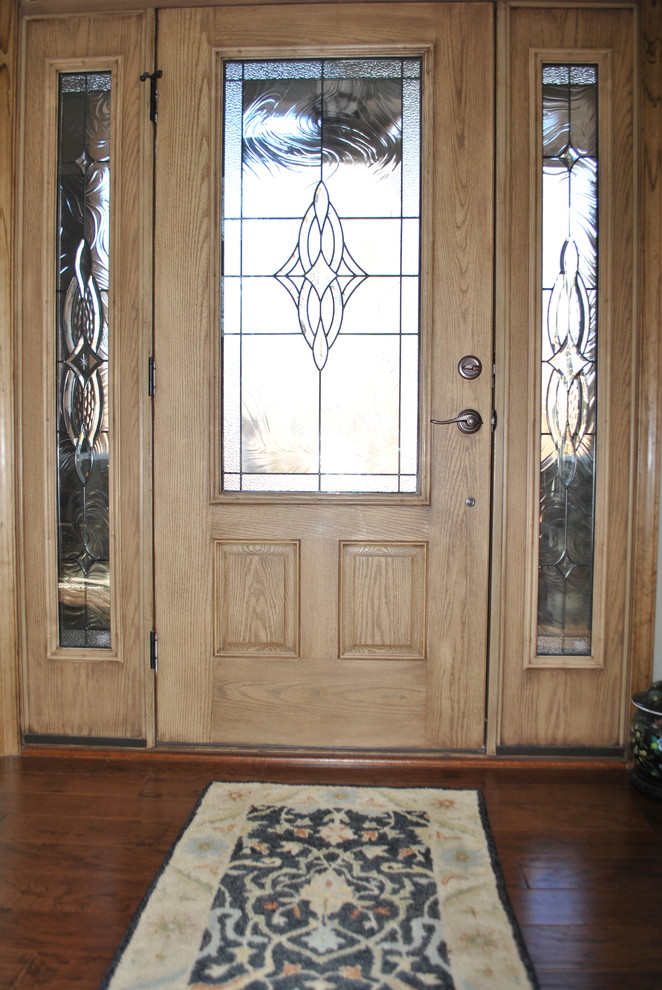 Imagen de puerta principal rural de tamaño medio con paredes grises, suelo de madera oscura, puerta simple, puerta de madera clara y suelo marrón