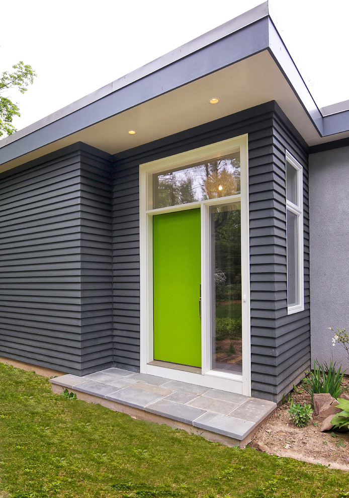 Modelo de entrada actual con paredes negras, suelo de pizarra, puerta simple y puerta verde