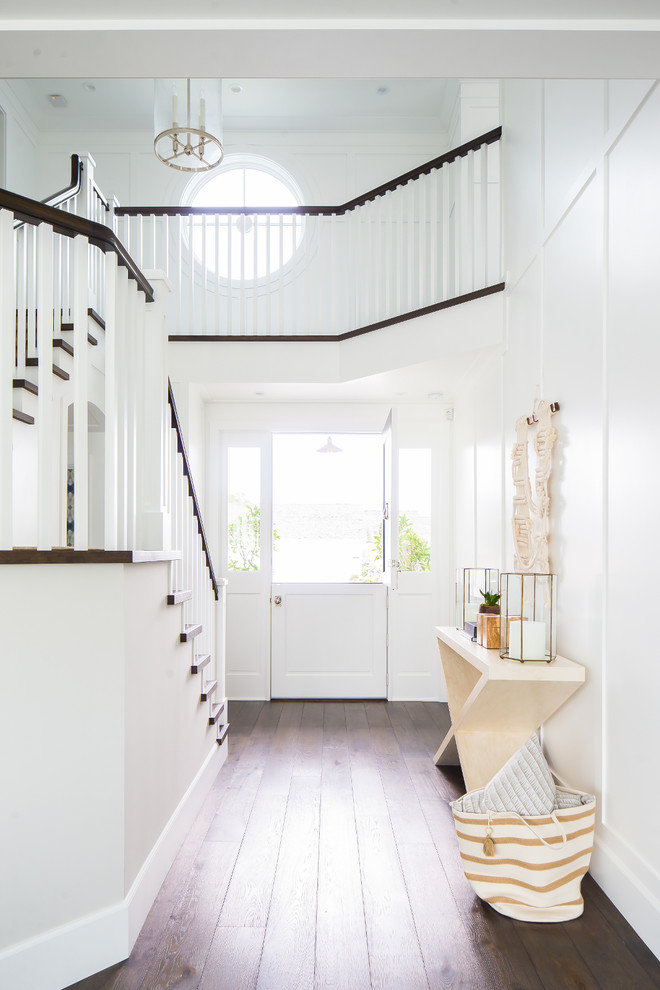 Photo of a coastal foyer in Orange County with white walls, dark hardwood flooring, a stable front door, a white front door and brown floors.