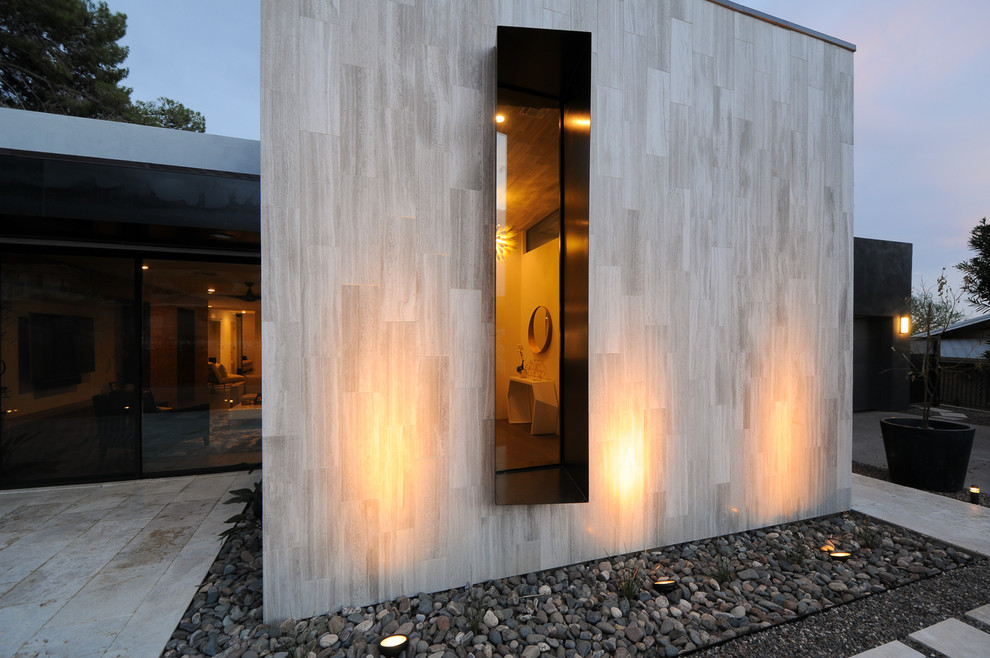 Imagen de puerta principal minimalista grande con paredes grises, suelo de madera en tonos medios, puerta pivotante, puerta de vidrio y suelo marrón
