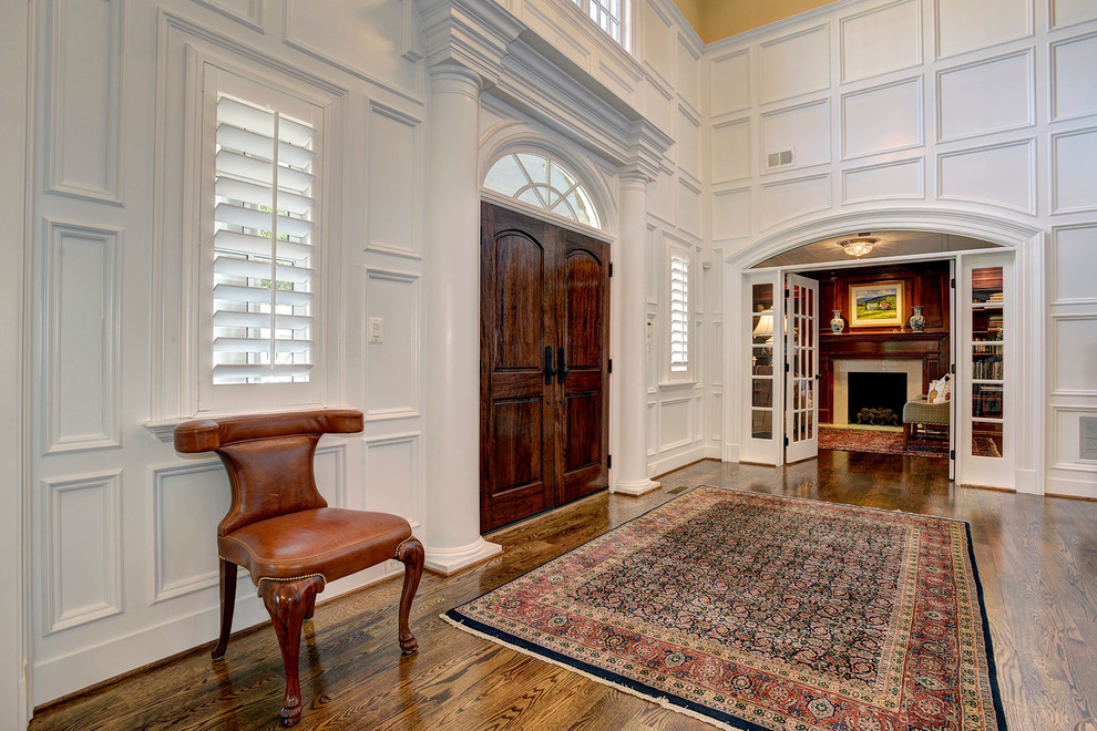 Aménagement d'un hall d'entrée classique avec un mur blanc, un sol en bois brun, une porte double et une porte en bois foncé.
