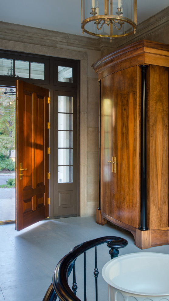 Пример оригинального дизайна: большое фойе в классическом стиле с бежевыми стенами, полом из известняка, одностворчатой входной дверью, входной дверью из дерева среднего тона и серым полом
