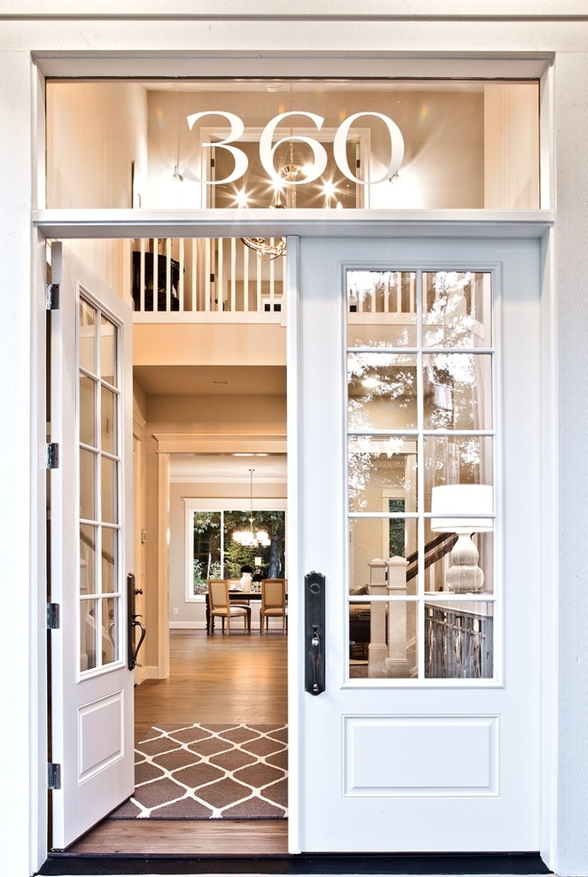 This is an example of a medium sized traditional front door in Seattle with a double front door, a white front door and feature lighting.