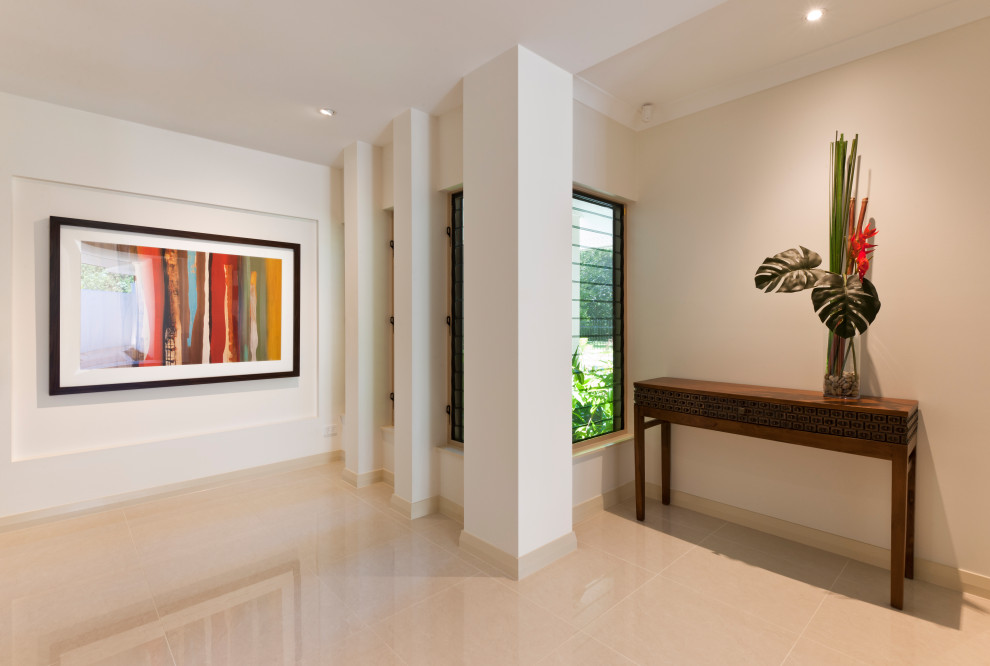 Bild på en mellanstor tropisk entré, med beiget golv, vita väggar, klinkergolv i porslin och en pivotdörr