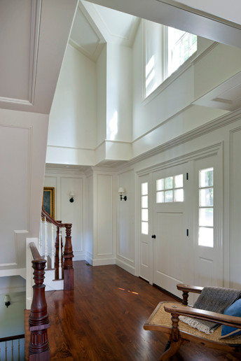 На фото: большое фойе в классическом стиле с белыми стенами, темным паркетным полом и поворотной входной дверью