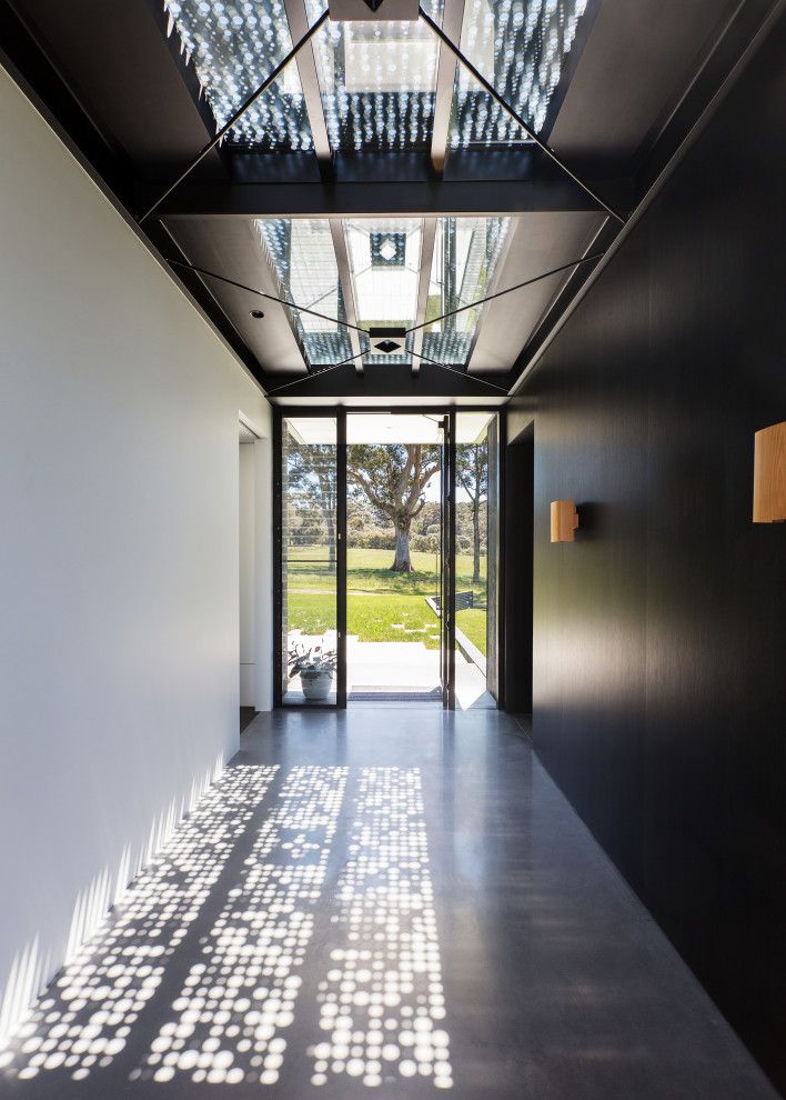 Идея дизайна: фойе с черными стенами, бетонным полом, одностворчатой входной дверью, стеклянной входной дверью и серым полом