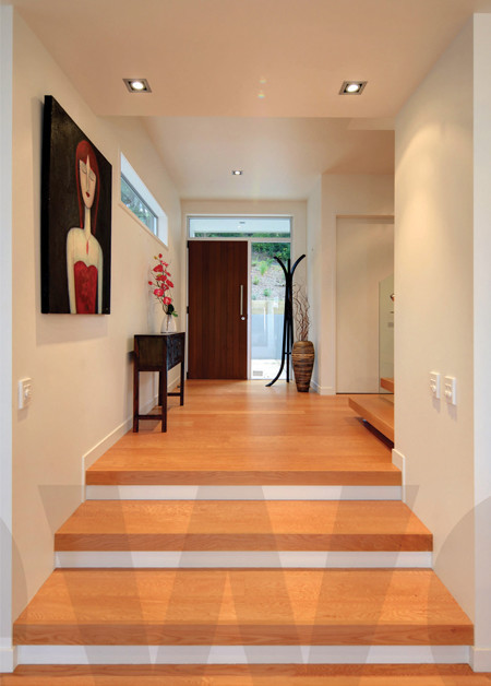 Idée de décoration pour un grand hall d'entrée design avec un mur blanc, un sol en bois brun, une porte simple et une porte en bois foncé.