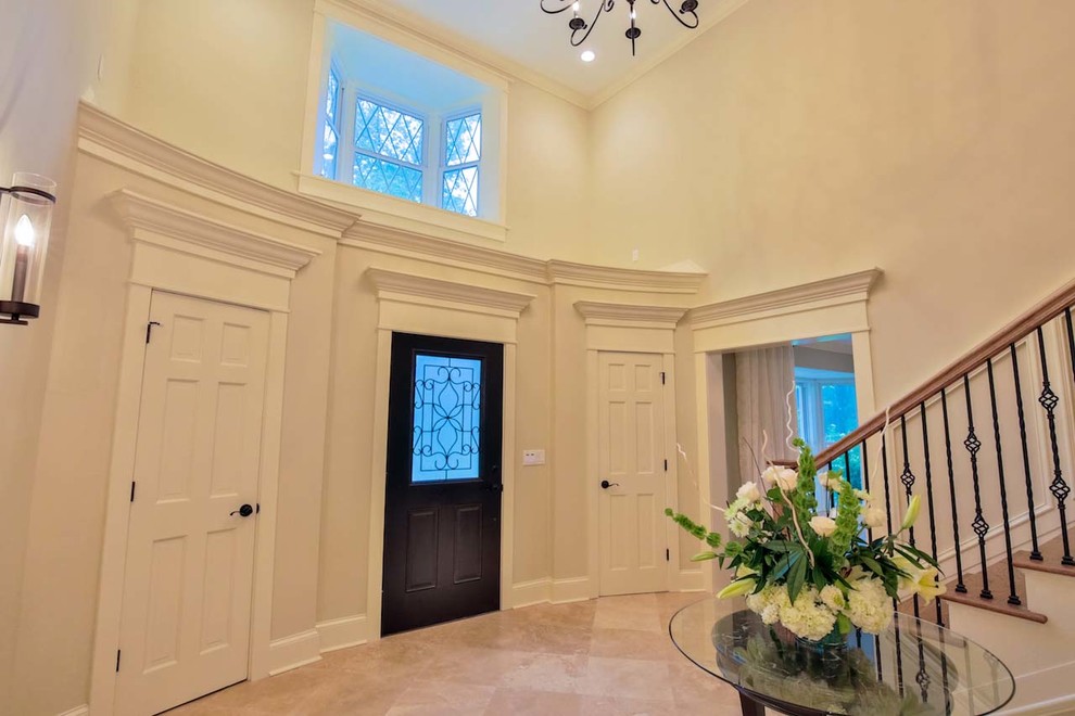This is an example of a large contemporary foyer in Atlanta with white walls, travertine flooring, a single front door and a dark wood front door.