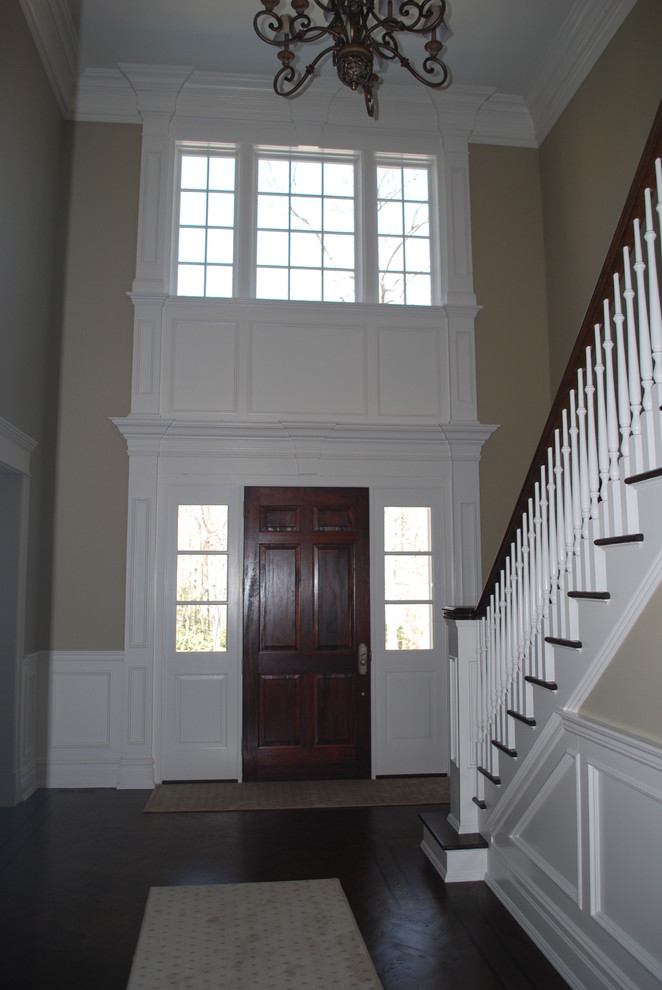 Imagen de hall tradicional grande con suelo de madera oscura y puerta simple