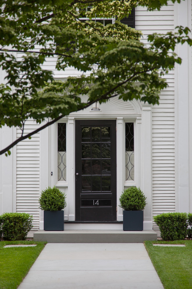 Cette image montre une porte d'entrée traditionnelle avec une porte simple et une porte noire.