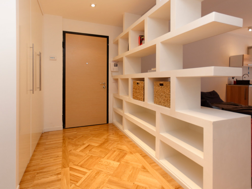 Mid-sized trendy light wood floor entryway photo in Milan with white walls and a light wood front door