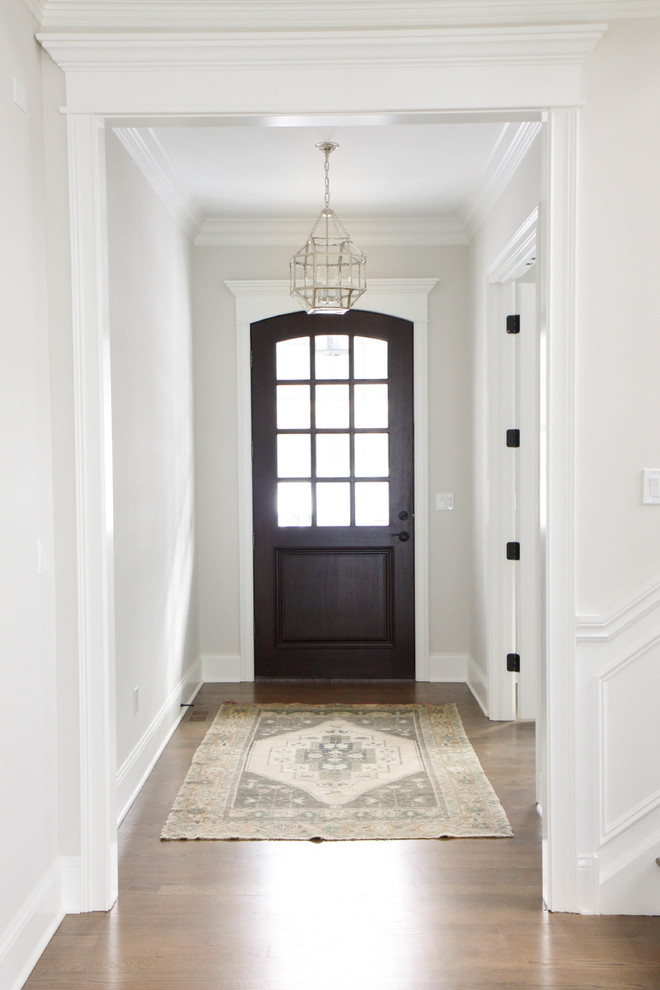 Foto de puerta principal clásica renovada de tamaño medio con paredes blancas, suelo de madera en tonos medios, puerta simple, puerta de madera oscura y suelo marrón