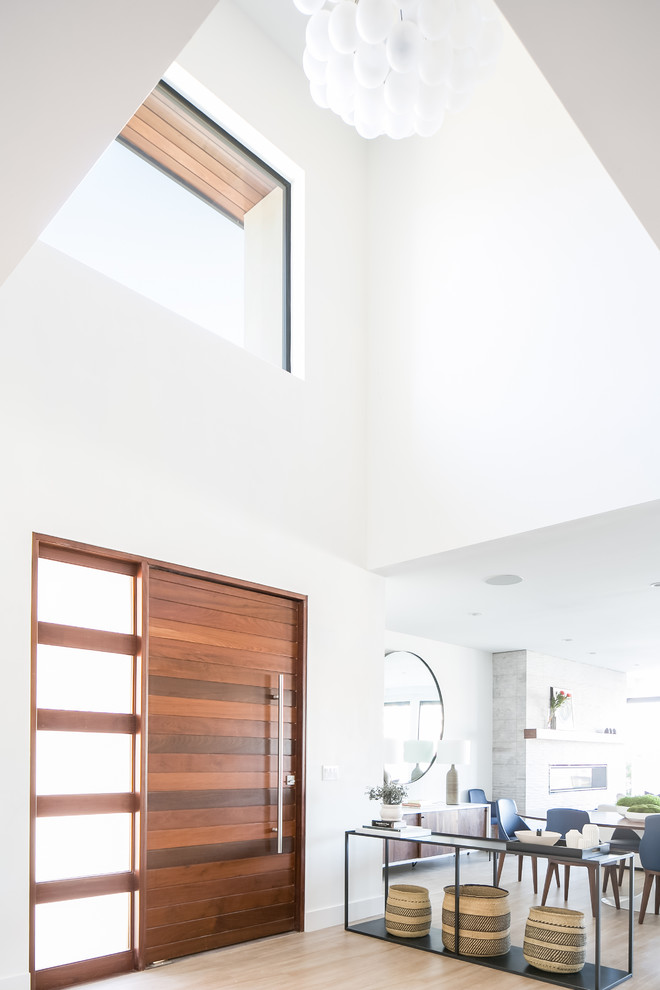 Idee per una grande porta d'ingresso minimalista con pareti bianche, pavimento con piastrelle in ceramica, una porta a pivot, una porta in legno bruno e pavimento beige
