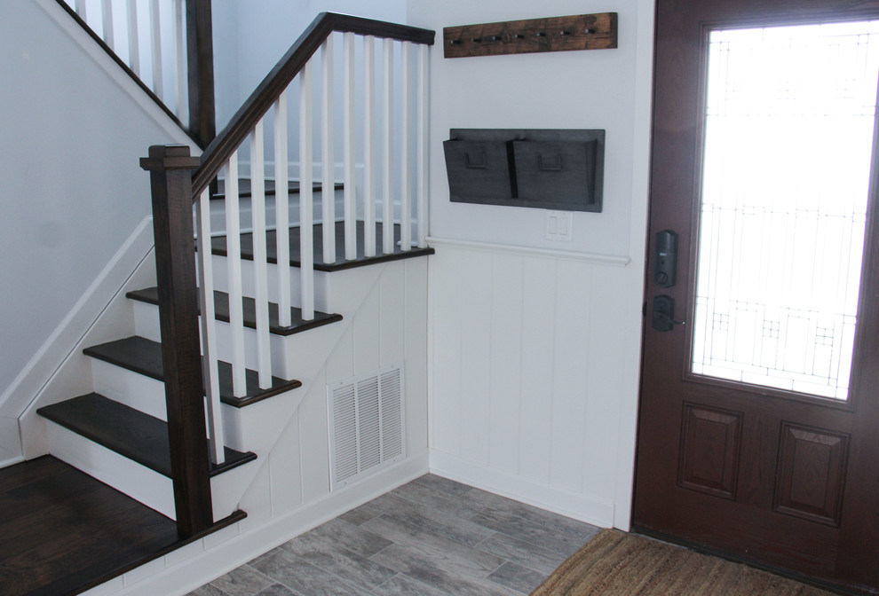 Exemple d'une porte d'entrée chic de taille moyenne avec un mur blanc, un sol en carrelage de porcelaine, une porte simple et une porte en bois foncé.